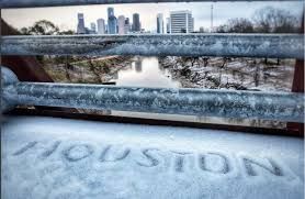 Snow covers Houston skyline and bridge railing.