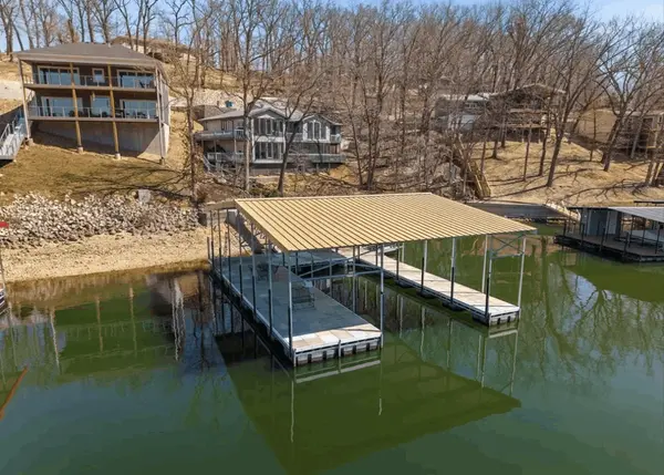 Lake of the Ozarks waterfront property with private covered dock, calm water views, and surrounding lake homes in a residential cove