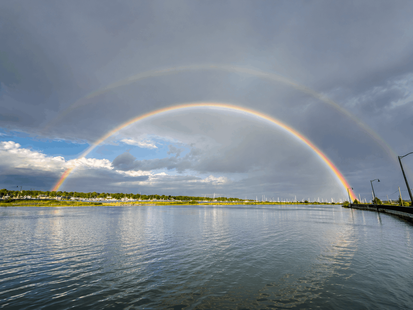Complete double rainbow reflected on the calm water of Padanaram Harbor