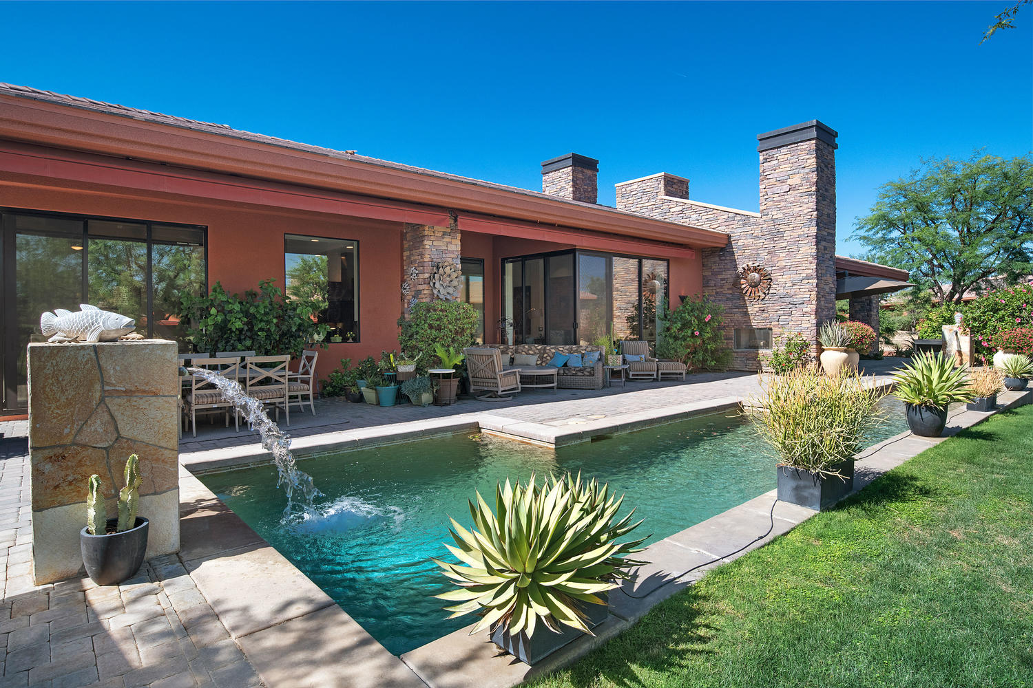 Contemporary Palmilla residence in La Quinta with stone architecture, private water feature, outdoor fireplace and desert landscaping
