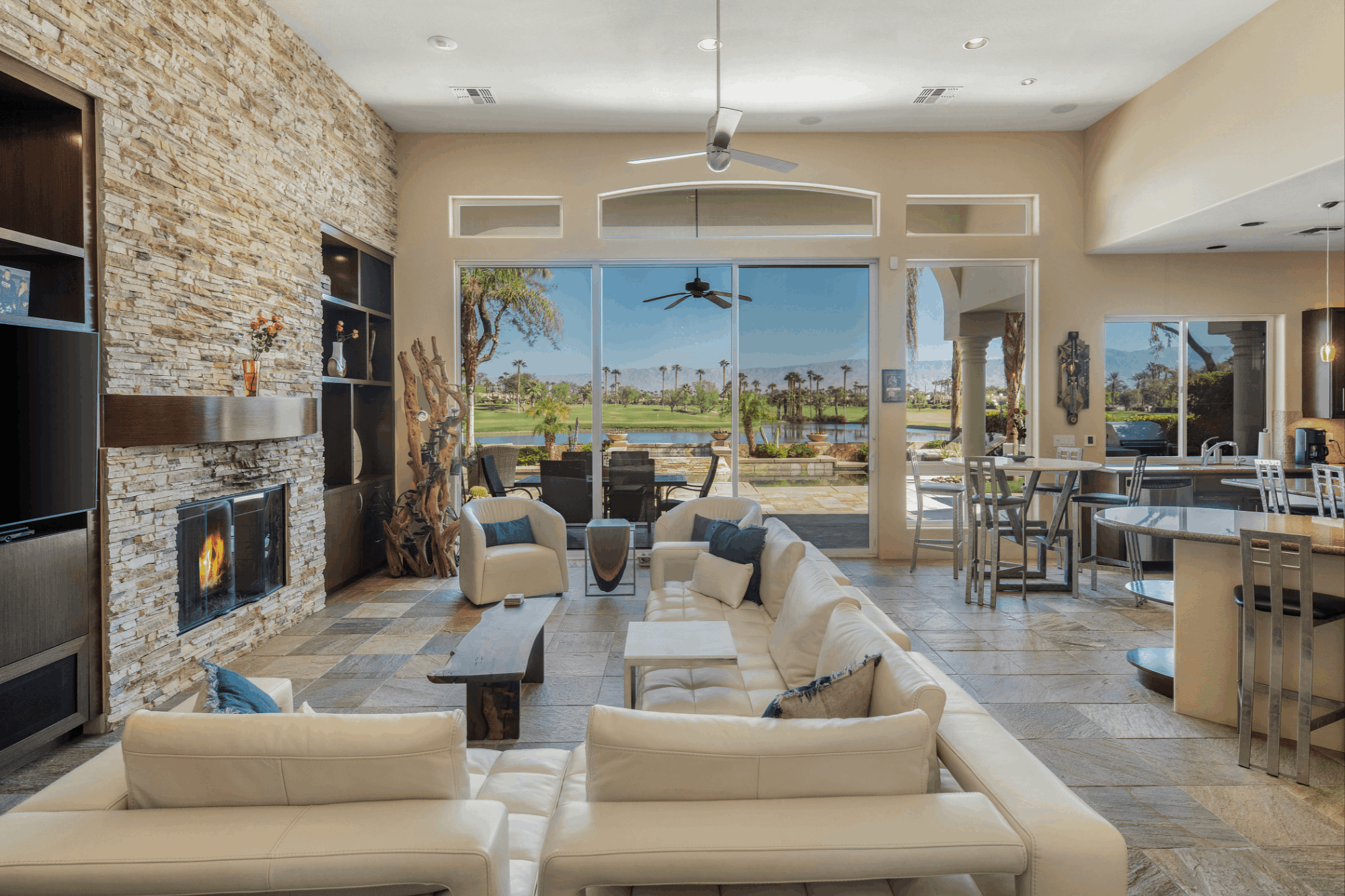 Interior of a Rancho La Quinta residence with expansive glass overlooking water, golf course fairways and mountain views