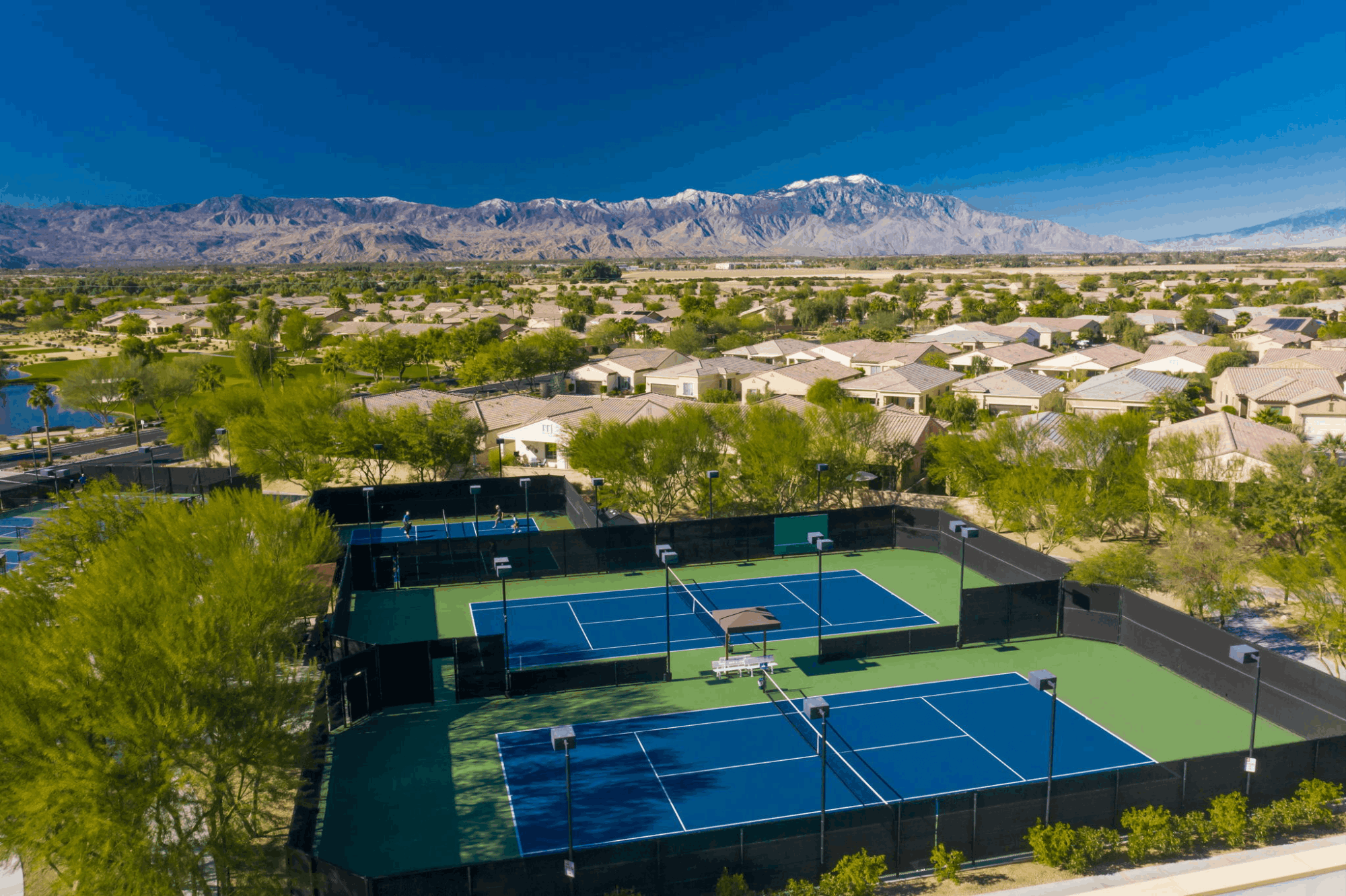 Tennis and recreation courts at Sun City Shadow Hills with Indio homes and mountain views beyond