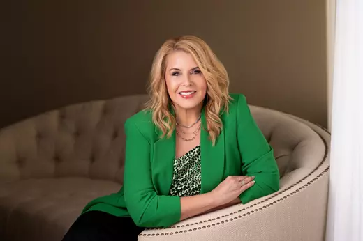 Shery Verdugo Sits in green blazer on beige couch, she is the best in the industry of Mortgage lending in reno and sparks NV. New home Northern Nevada Real Estate Team Mortgage preapproval Home buying process Buying a house in Reno and Sparks NV