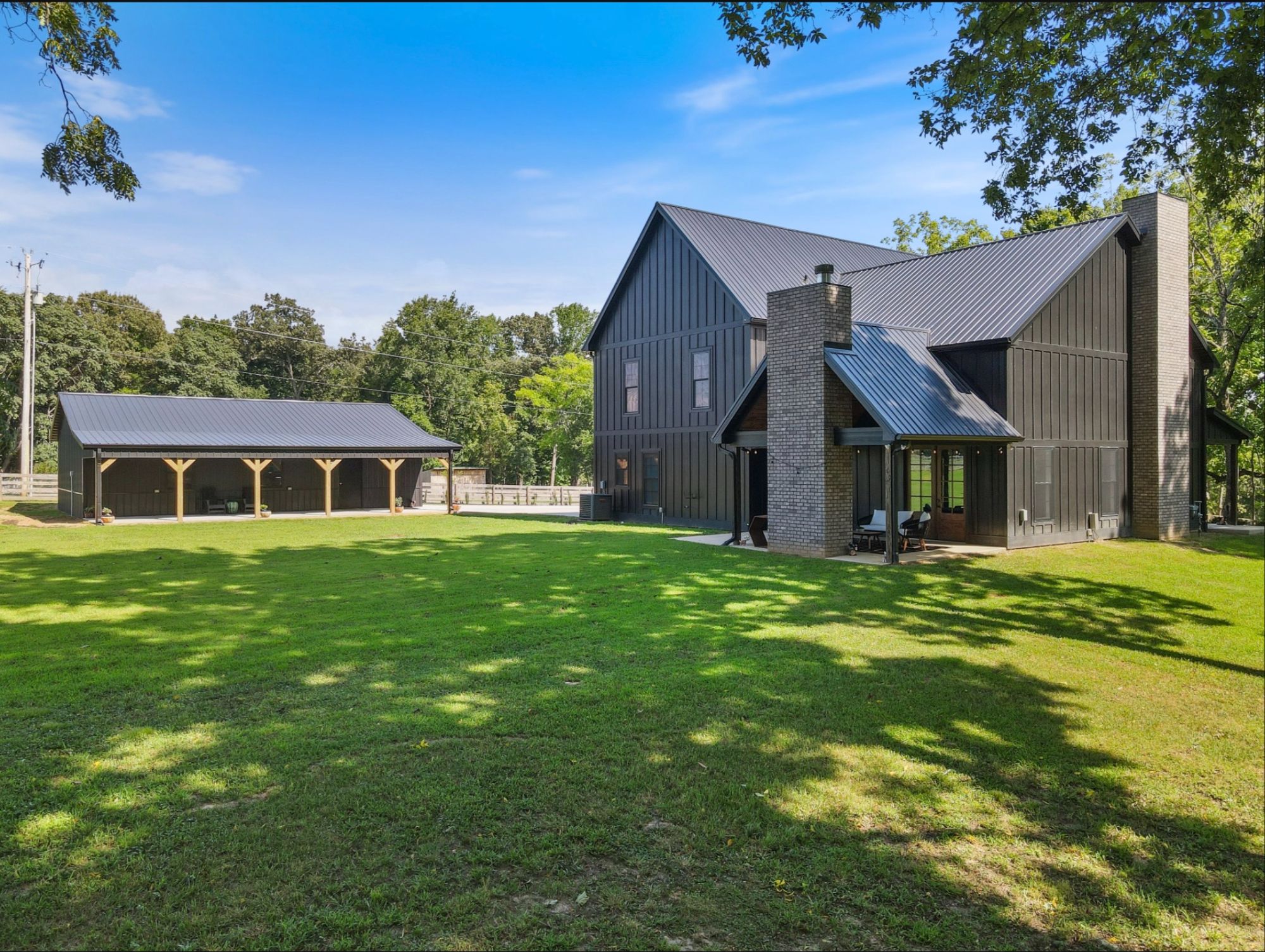 Modern farmhouse with a detached barn on a wide lawn