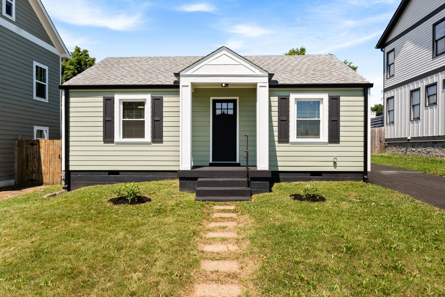 Sage green cottage with a white portico and front walk