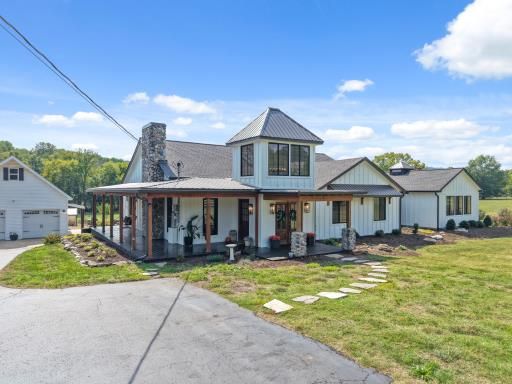 White farmhouse with a wraparound porch on open land
