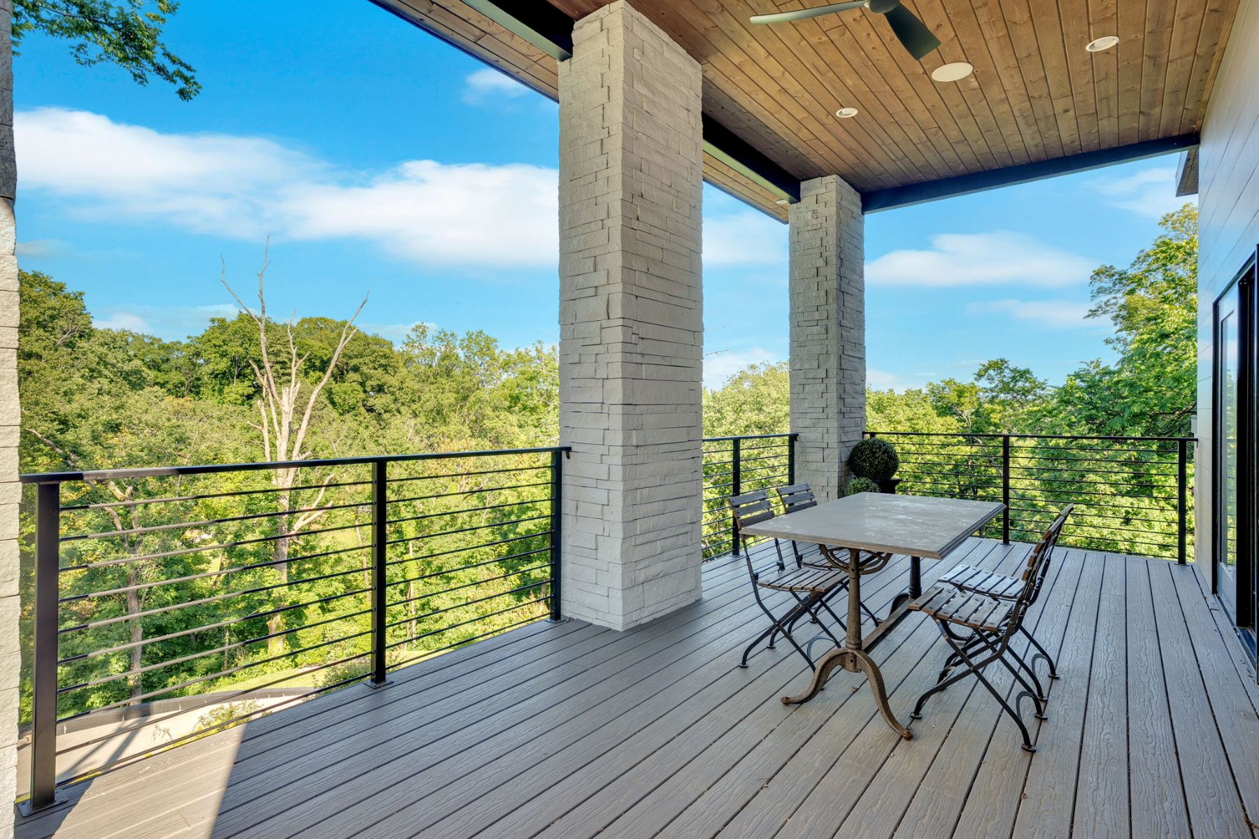 Covered deck with a dining table overlooking a wooded hillside