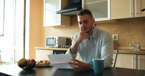 a homeowner reviewing mortgage or household paperwork at a kitchen table