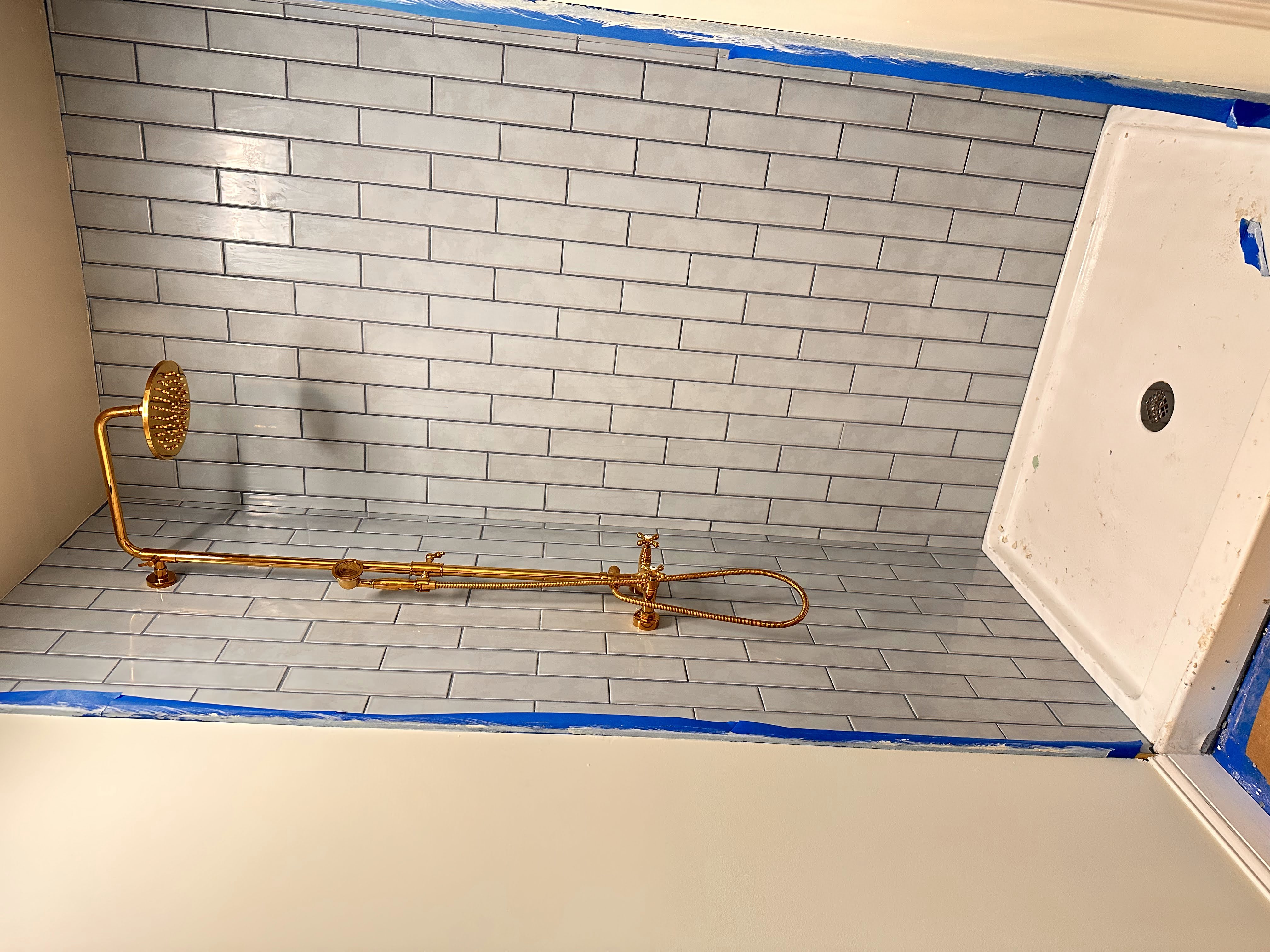 The primary bathroom tile and brass shower fixture.