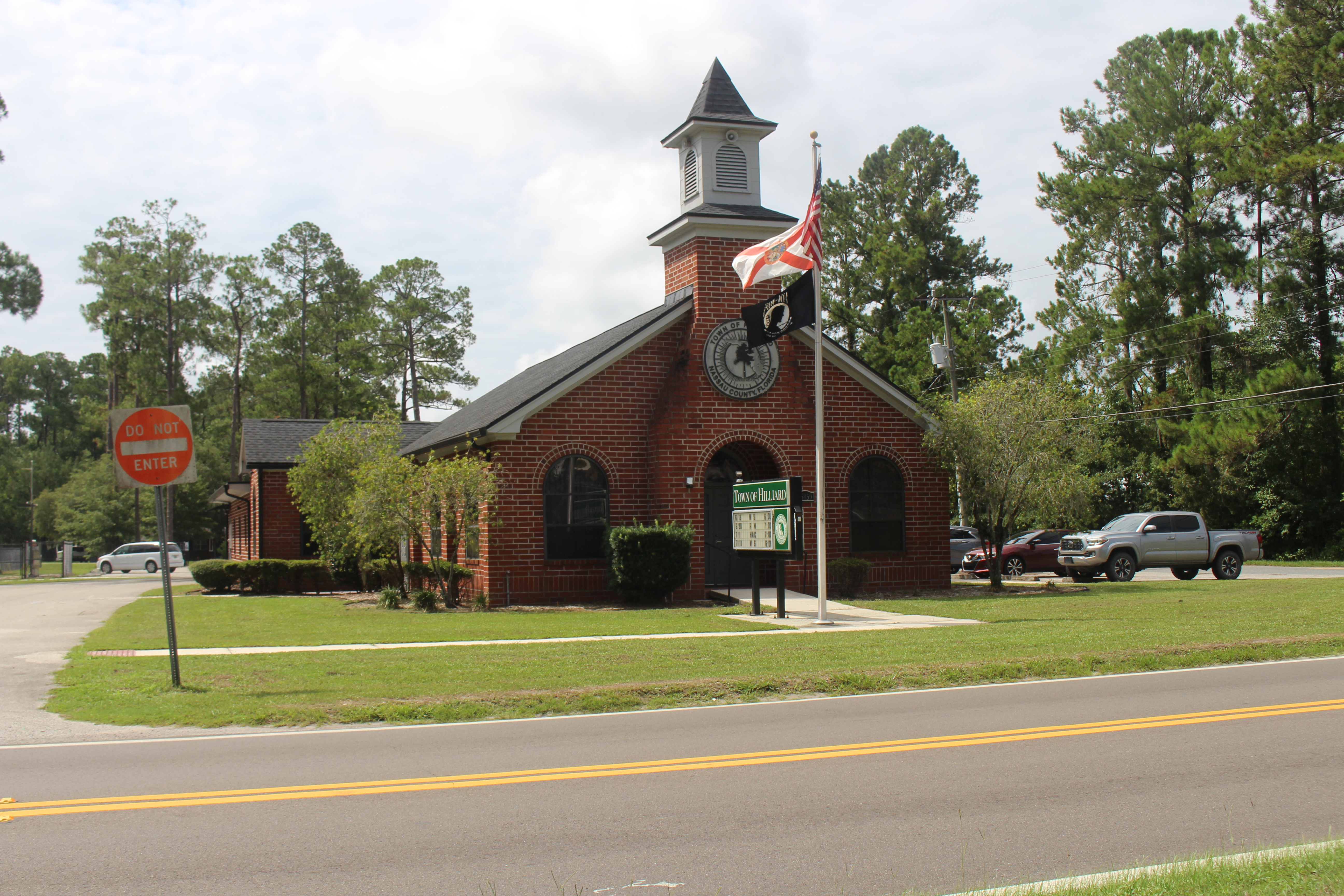 Ranch-style home on open acreage with a fence line and pines in Hilliard, Florida