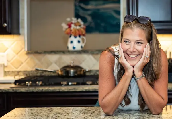 Erin O’Brien, Coastal Virginia Realtor, smiling in a warm kitchen setting, representing a welcoming real estate experience.