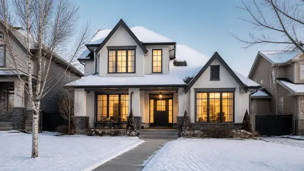 Calgary home on a winter afternoon with a shovelled walkway and warm interior lights
