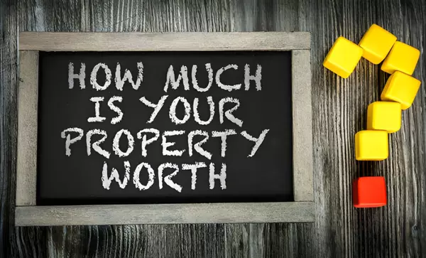 Real estate concept image showing the question “How much is your property worth?” on a chalkboard, symbolizing home valuation and property assessment.