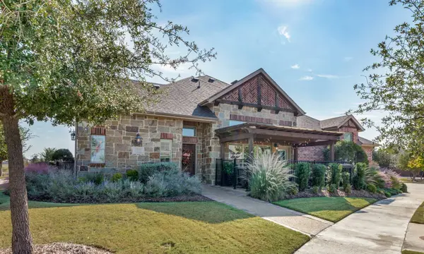 A stone-front Texas home with a pergola and drought-tolerant landscaping