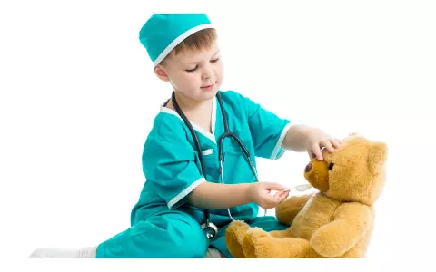 Little boy in scrubs playing doctor with teddy bear