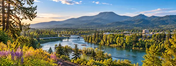 Riverside Town Beneath Forested Mountains