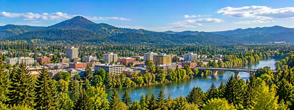 Riverfront City Beneath Forested Mountains