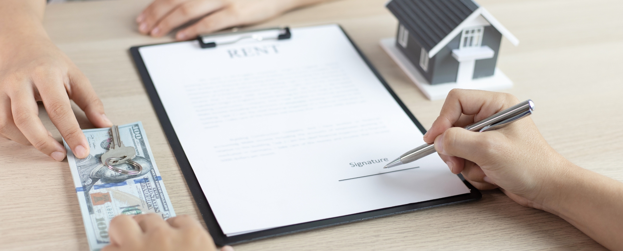 Landlord signing rental property documents beside house keys and cash, representing rental property finances, utility responsibilities and property management.