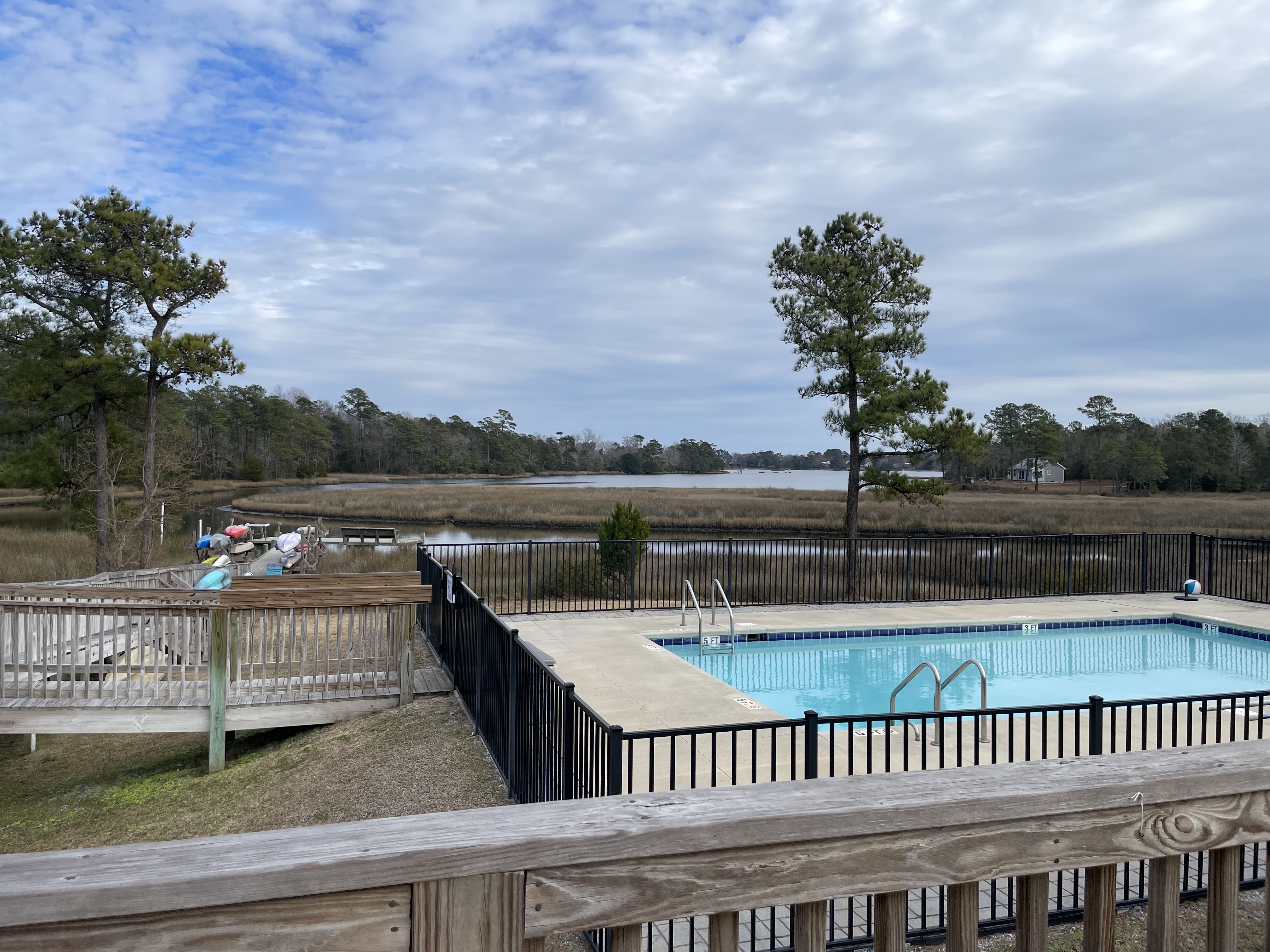 Photo of a community swimming pool, in Huber, NC, located on the edge of marsh waters, and showing kayak storage near the water.
