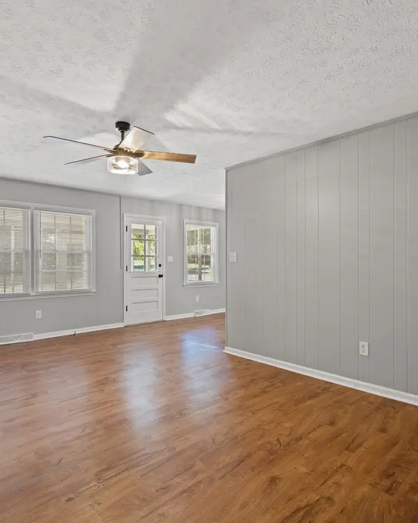 Living room with new wood-look plank flooring, fresh gray paint, and a ceiling fan