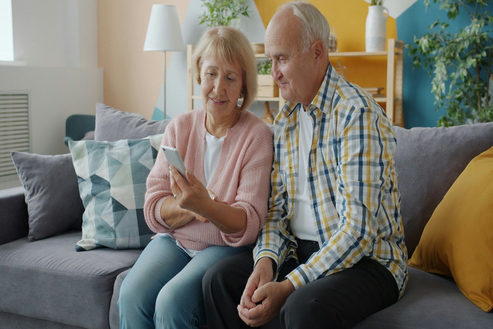 Couple on their couch looking at a phone while running the numbers on downsizing their South Denver home