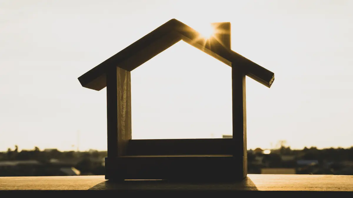 Wooden house silhouette with sunlight behind it representing Portland real estate.