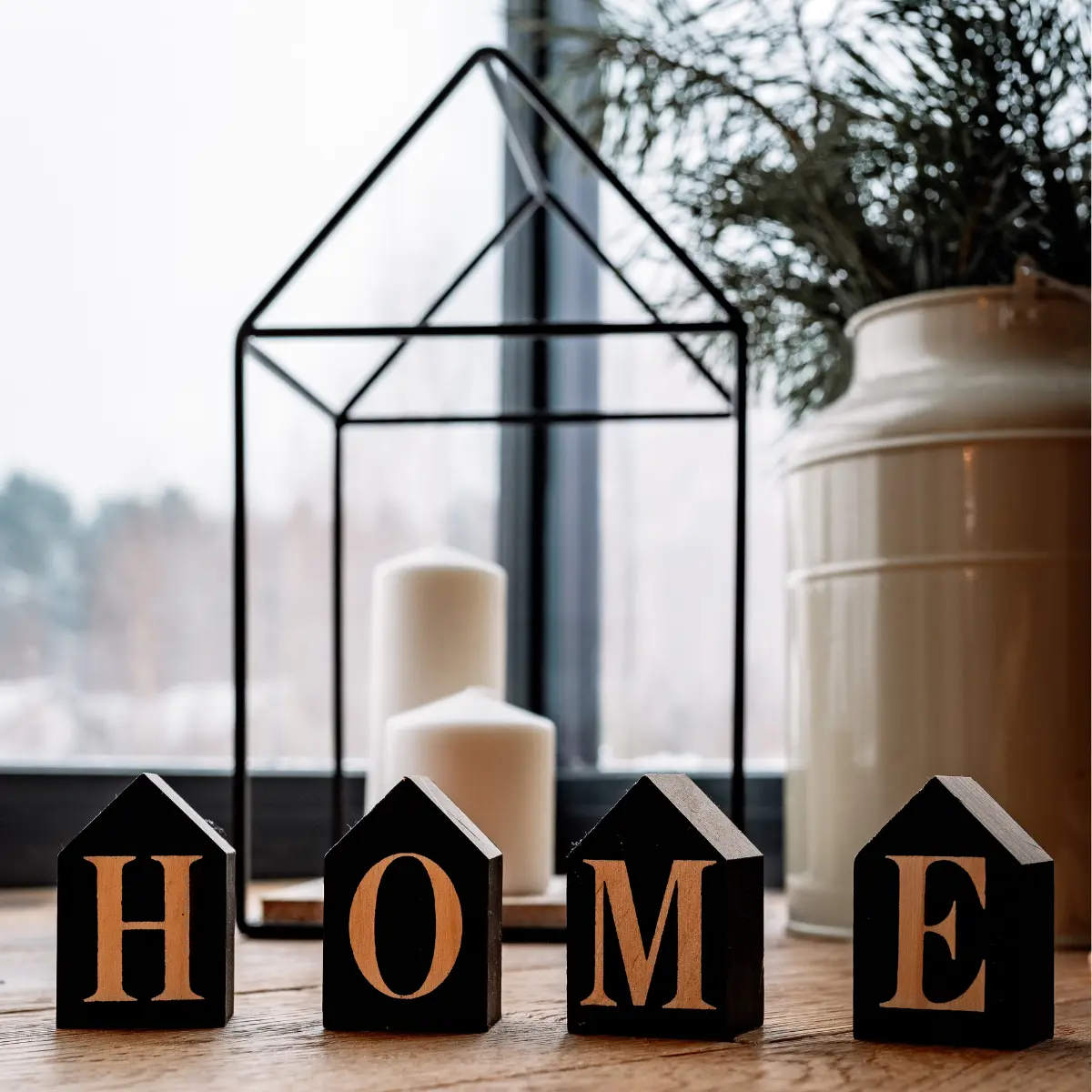 Decorative HOME blocks and candles on a windowsill, representing finding a new home with a Portland Real Estate Agent