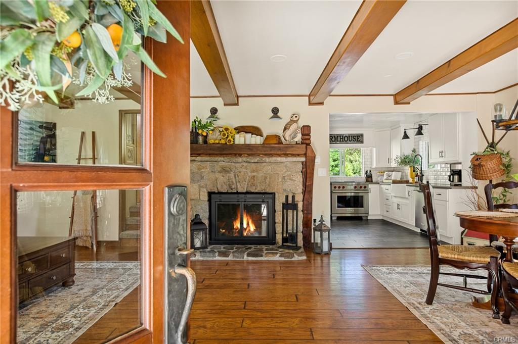 Inviting Lake Arrowhead mountain home interior with stone fireplace, wood beams, and open farmhouse-style kitchen viewed from the front door.