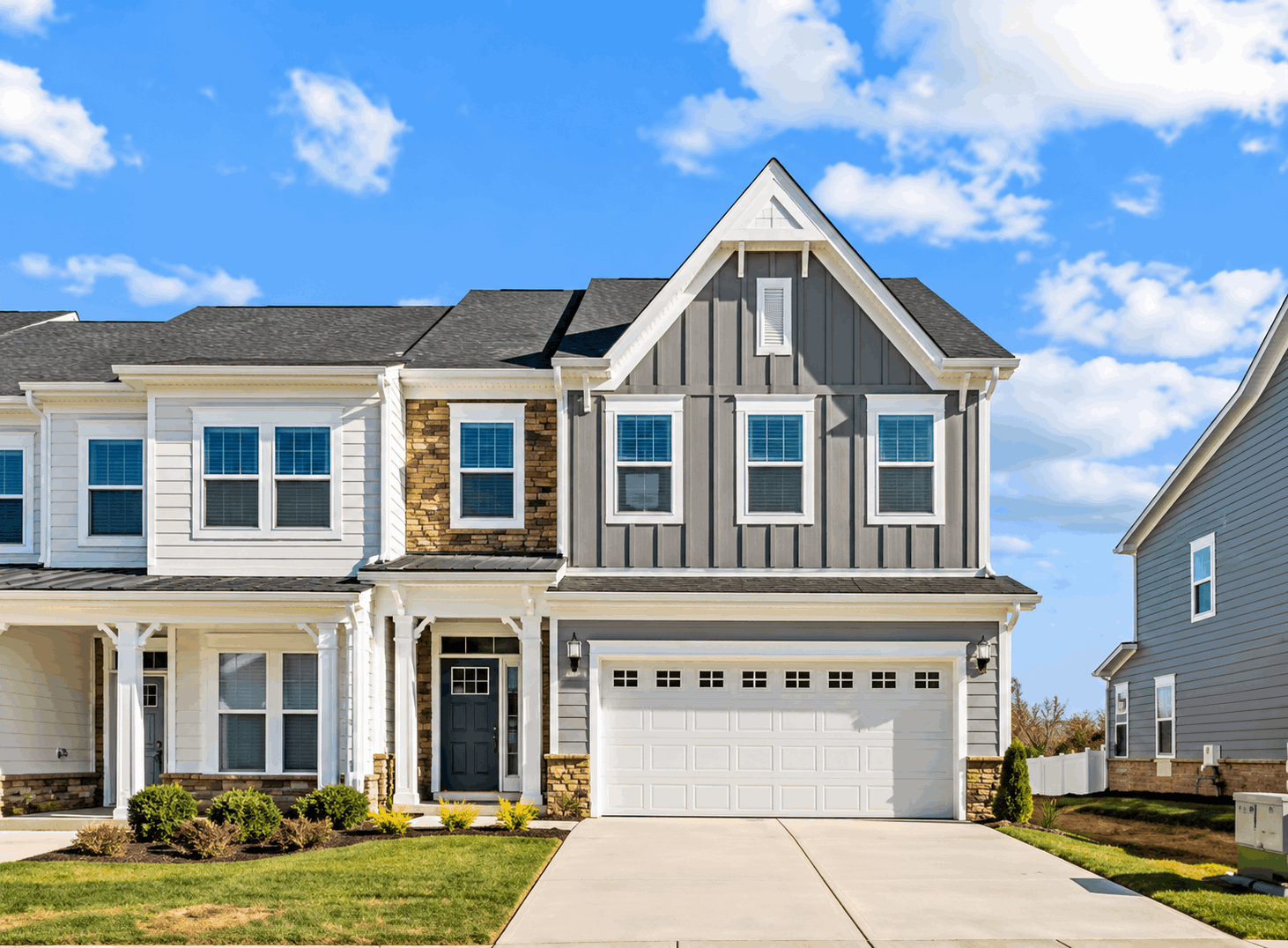 New construction townhome with board-and-batten siding, stone accents, and a two-car garage in White Plains, MD