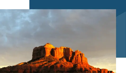 Landscape photo of red rock cliffs and cloudy sky, approximate aspect ratio 520x320, used as illustrative image of Sedona scenery