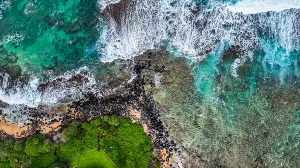 blue-ocean-waves-washing-against-volcanic-rock-on-the-coastline-of-a-remote-hawaiian-b-SBI-350795241