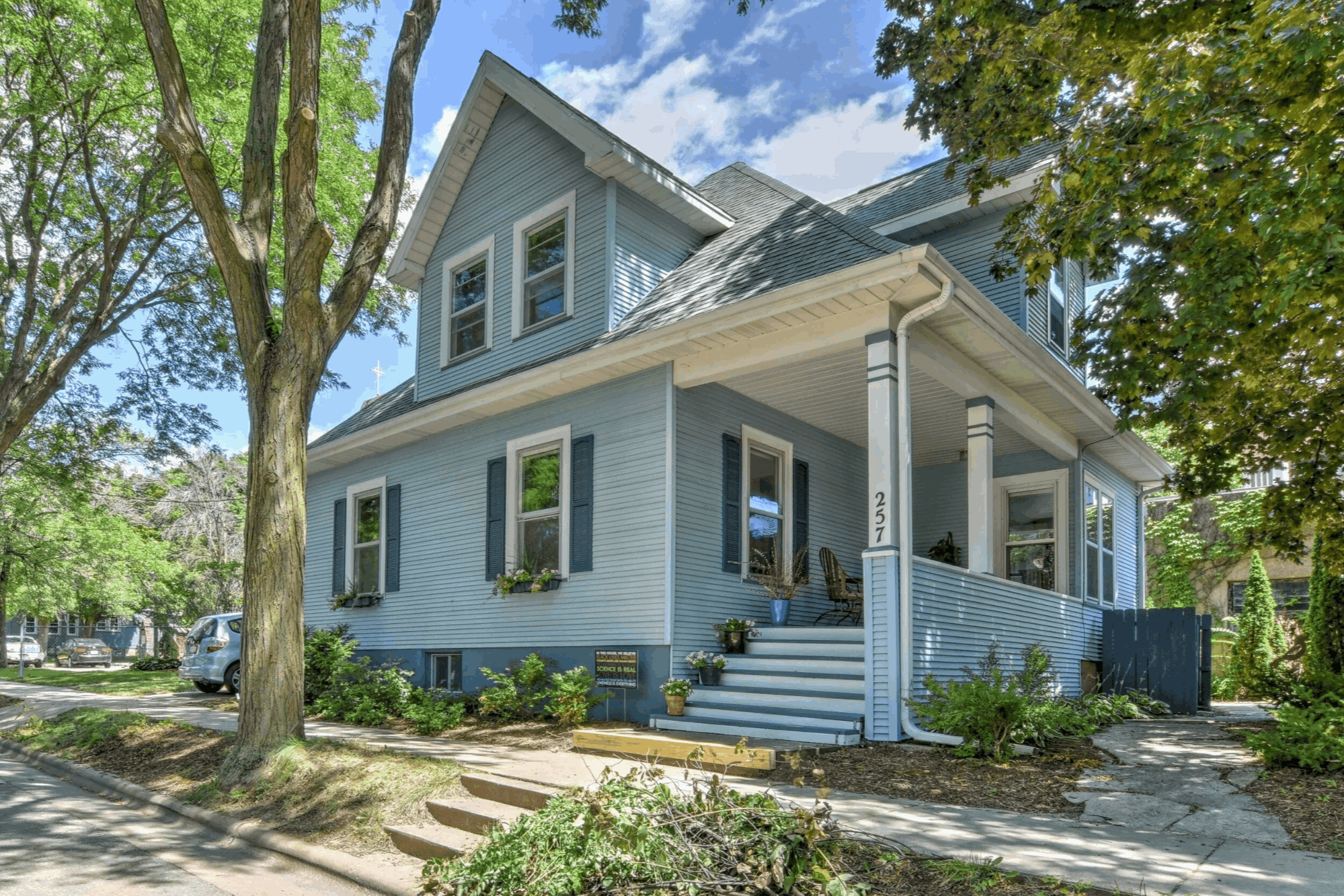 Photo of a classic residential house with porch and trees, landscape orientation