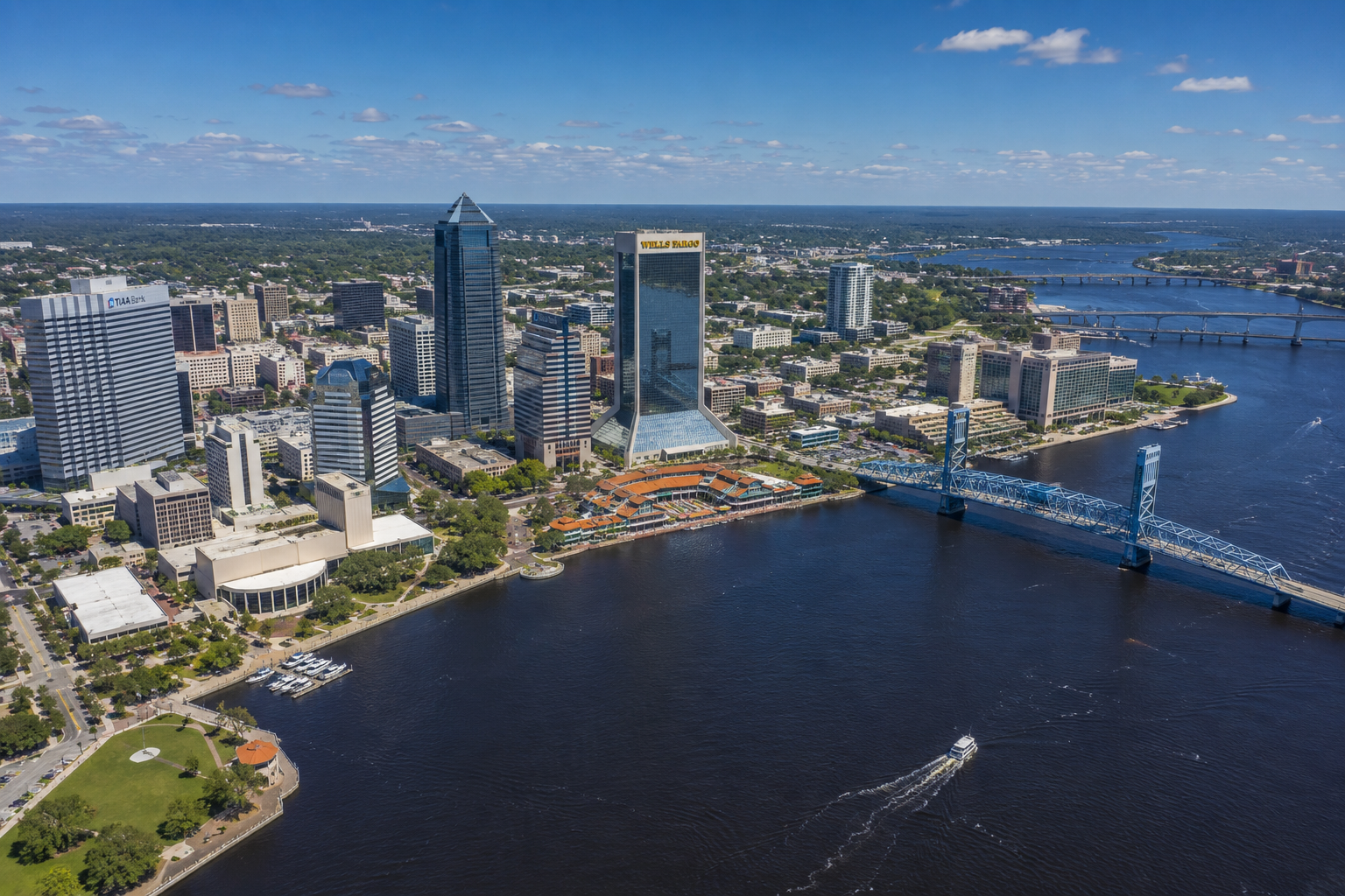 "Aerial view of downtown Jacksonville, Florida skyline along the St. Johns River featuring waterfront parks, office towers, and city living in Northeast Florida."