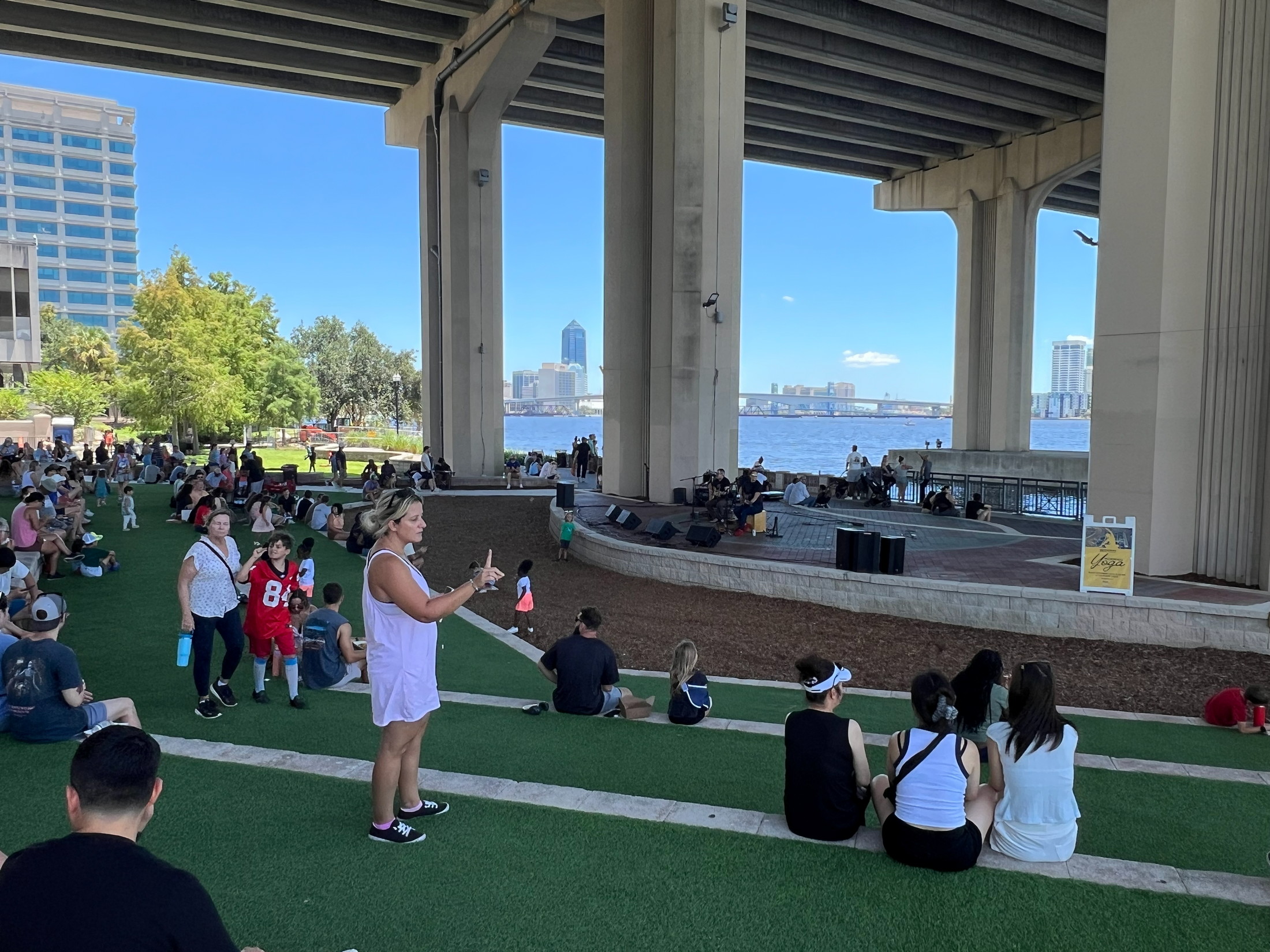 Diverse community gathering for live music beneath the Fuller Warren Bridge in Jacksonville, Florida.