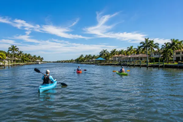 Kayakers paddling along the Jacksonville Intracoastal Waterway surrounded by waterfront homes and tropical landscaping.