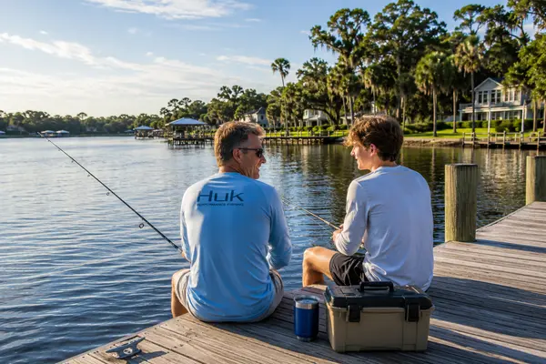 Middle-aged man and a high school-aged teen fishing from a private dock on the St. Johns River in Mandarin, Jacksonville, Florida, enjoying the area's peaceful waterfront lifestyle.