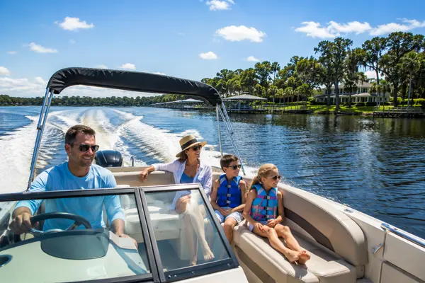 Family enjoying a sunny day boating on the St. Johns River in Mandarin, Jacksonville, with waterfront homes and private docks highlighting the community's river lifestyle.