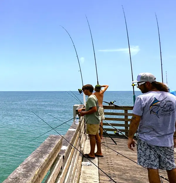 People fishing from the Jacksonville Beach Pier overlooking the Atlantic Ocean, highlighting one of the area's most popular waterfront activities.