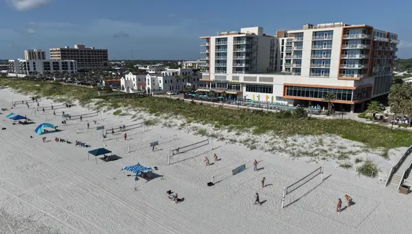 Aerial view of beach volleyball courts, sandy shoreline, and oceanfront buildings in Jacksonville Beach, Florida.