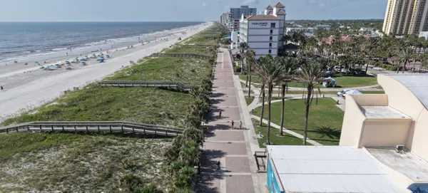 Aerial view of an oceanfront walkway running beside the beach and residential buildings in Jacksonville Beach.