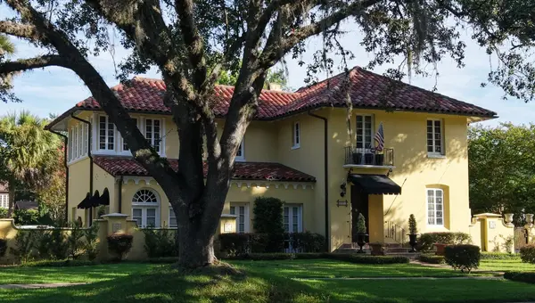 Historic stucco home with a red tile roof beneath a mature live oak in Avondale, Jacksonville, Florida.