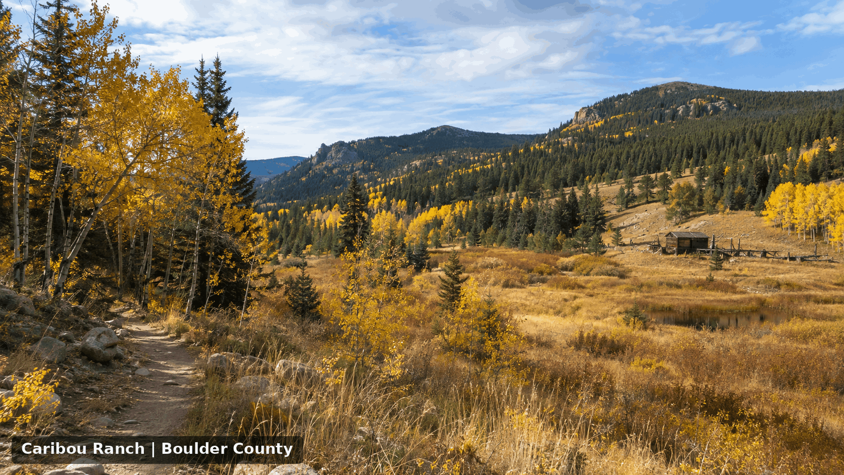 Caribou Ranch in Boulder County during fall with golden aspens, open mountain meadow, evergreen forest, historic ranch scenery, and Rocky Mountain terrain.