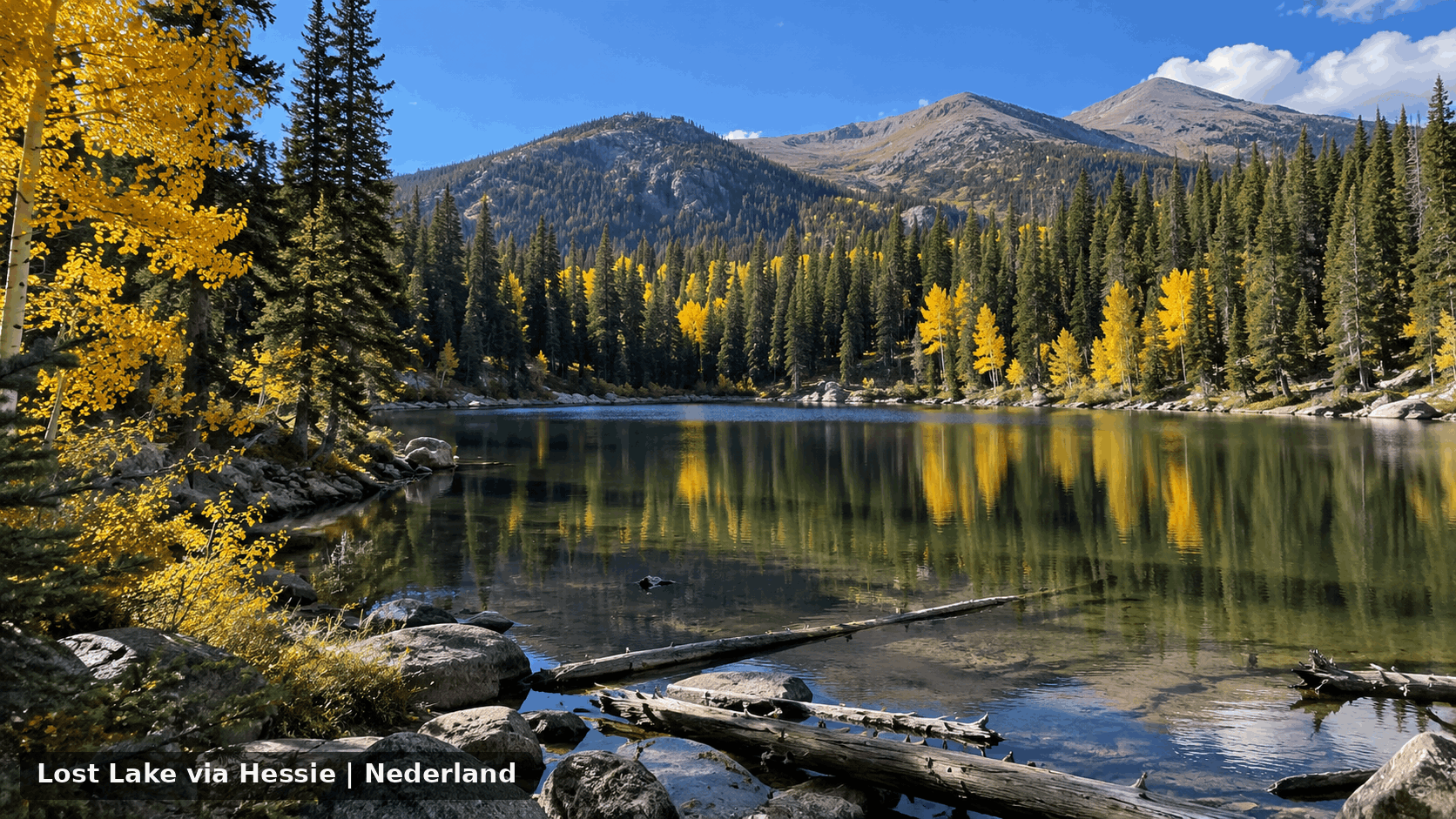 Lost Lake near Hessie Trailhead outside Nederland, Colorado, surrounded by evergreen forest, golden aspens, mountain slopes, rocks, and fall foliage.