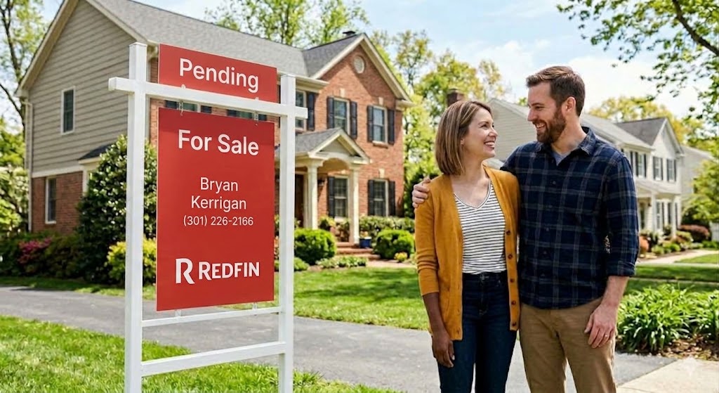 A happy couple standing in front of a suburban house with a prominent Redfin SOLD sign, illustrating successful home sales and purchases during Maryland's housing inventory drought.