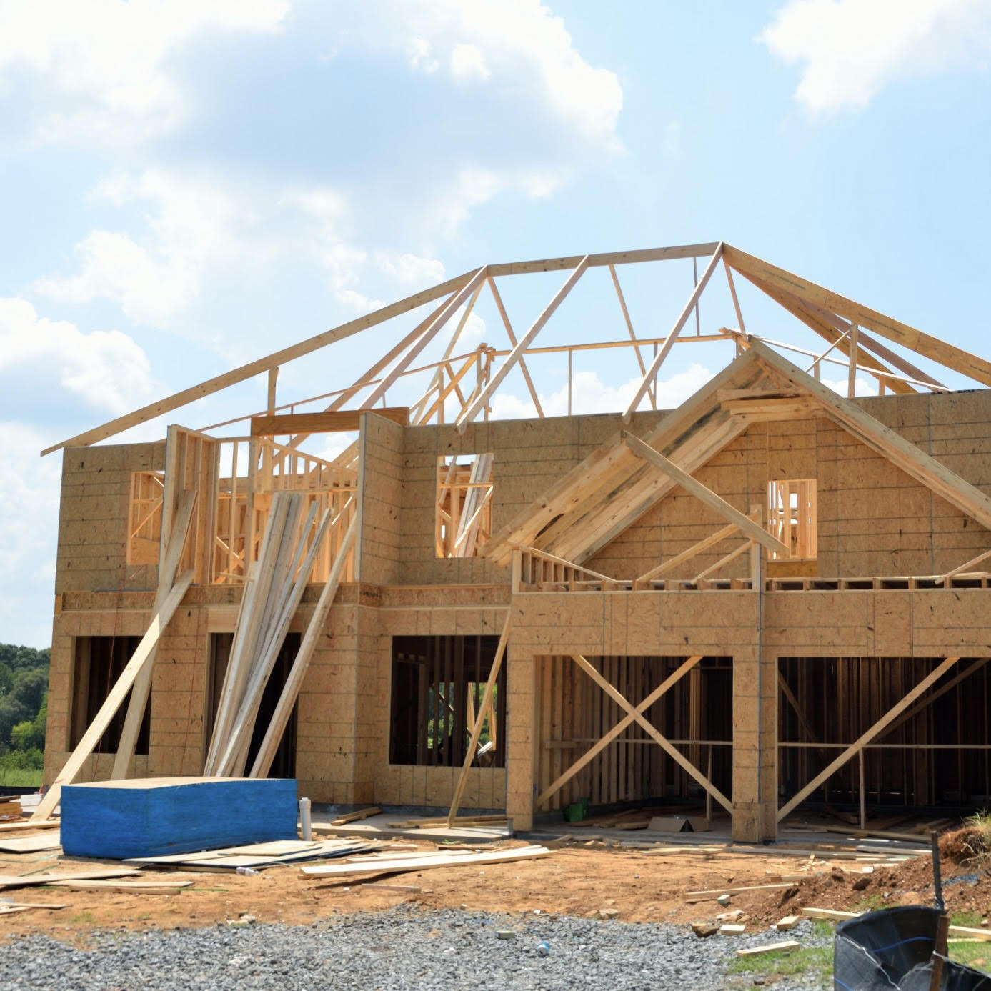 A new construction home under development at the framing stage with wooden roof trusses exposed, illustrating why buyers should closely monitor and photo-document a house build to catch builder mistakes.