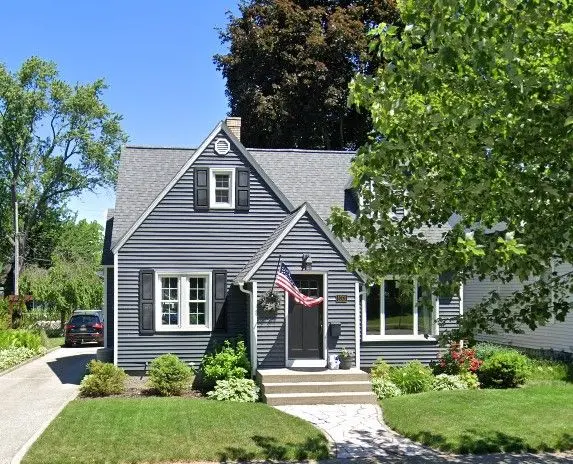 Gray Cape Cod-style home with white trim, landscaped front yard, and welcoming entryway