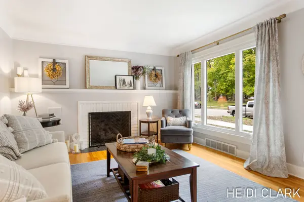 Bright, inviting living room featuring a white fireplace, hardwood floors, large windows, and comfortable seating.
