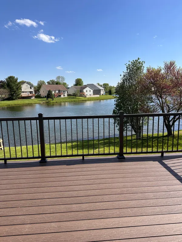 Spacious backyard deck overlooking a peaceful pond, with beautiful water views, mature trees, and blue skies. 💙