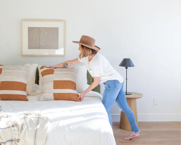 Stock - woman in hat fluffing pillow