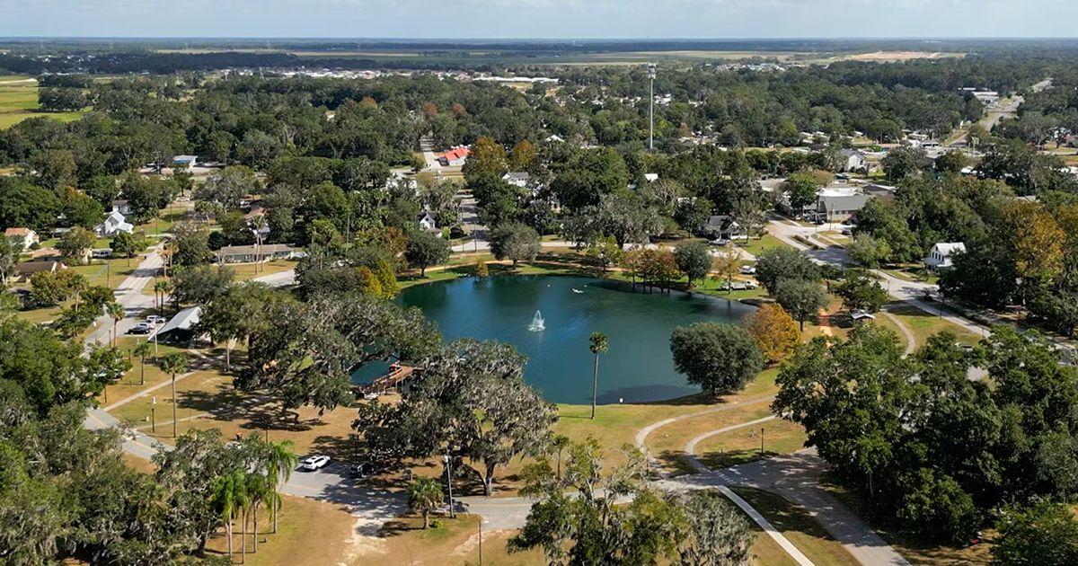 Aerial view of town park with fountain pond and tree-lined streets in Belleview Florida Marion County